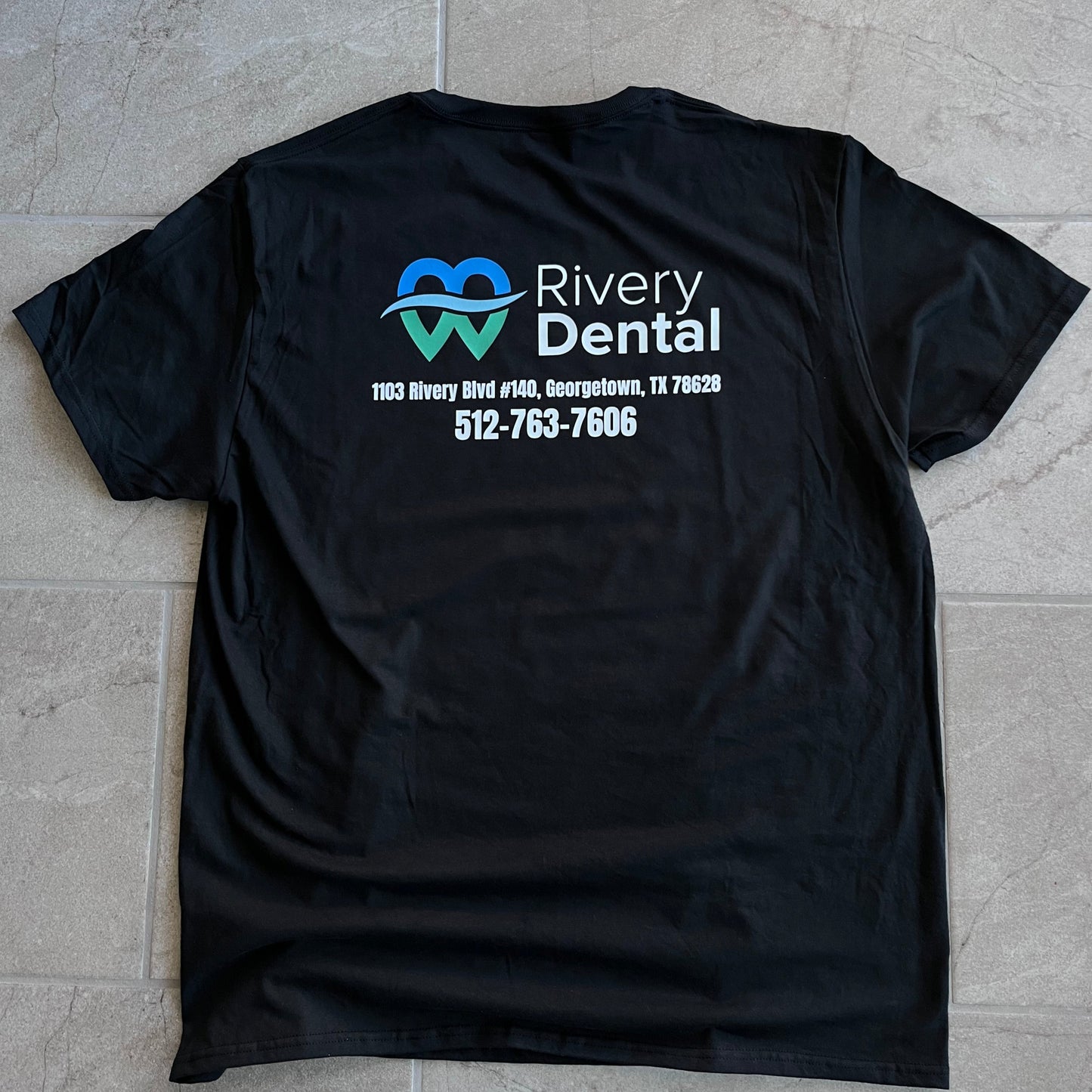 Black t-shirt with Riverview Dental logo on a tiled floor. Custom t-shirt, logo personalized design, men’s/unisex fit, front/back view.. custom personalized t shirt unisex kid youth adult women men crew neck polyester moisture wicking cotton soft comfortable