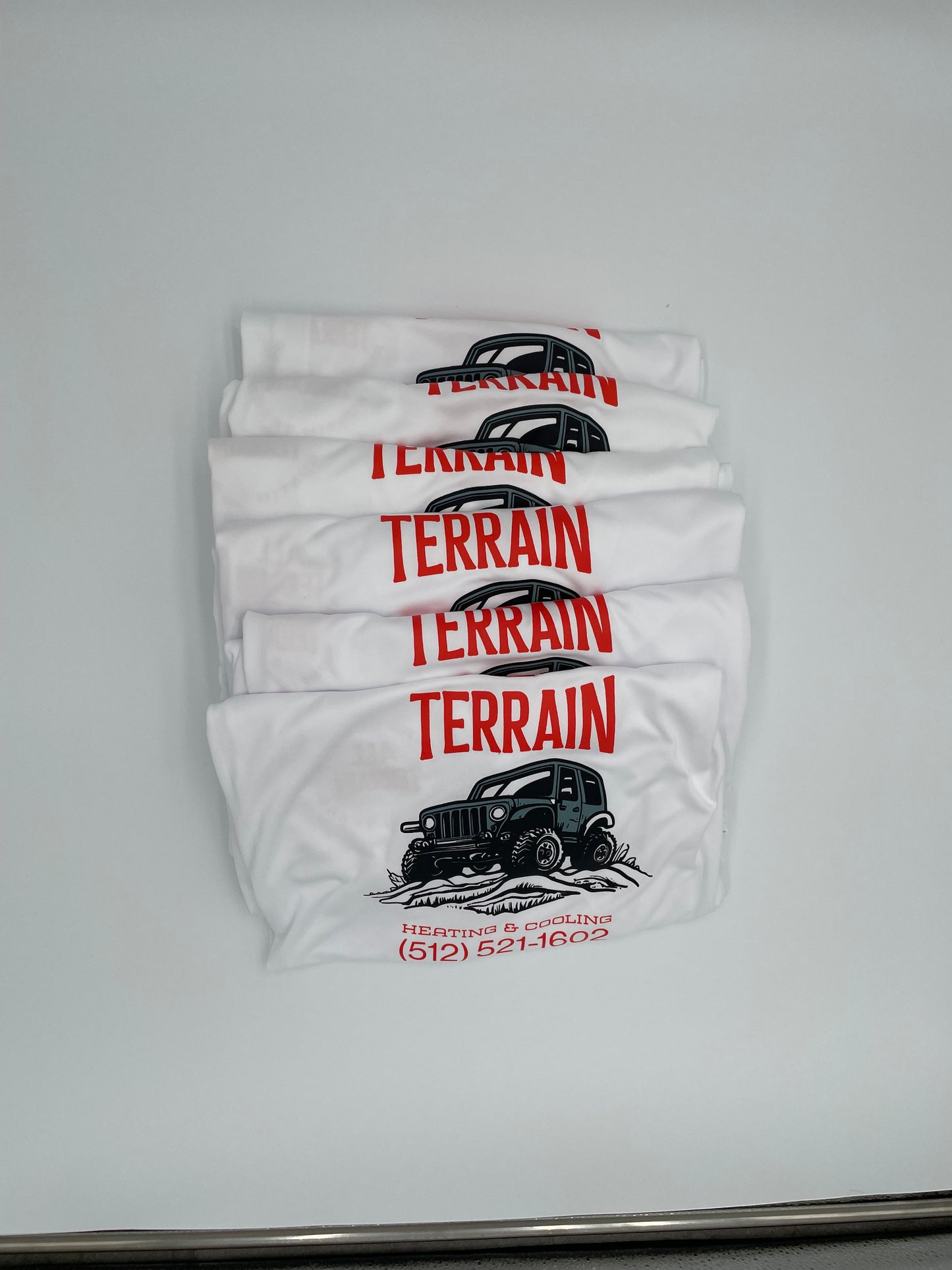 Four white t-shirts with 'TERRAIN' branding on a light gray background. Custom t-shirt, logo personalized design, men’s/unisex fit, front/back view. . custom personalized t shirt unisex kid youth adult women men crew neck polyester moisture wicking cotton soft comfortable