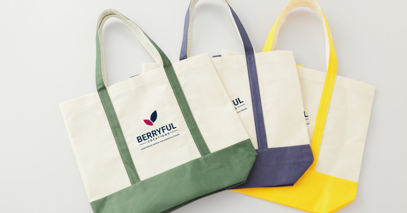 Branded tote bags, notebooks, pens, and drinkware displayed as promotional giveaways for a trade show