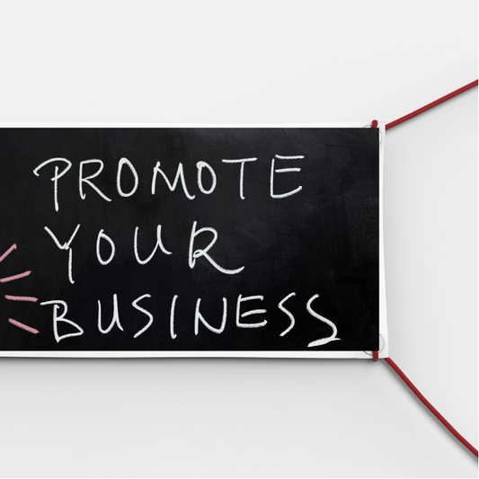 A black mesh banner with the text 'PROMOTE YOUR BUSINESS' written in white marker, folded and secured with a red tie.13oz vinyl banner