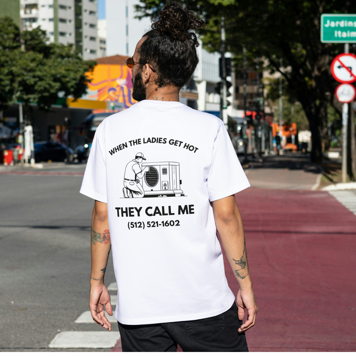 Person wearing a white t-shirt with text and a graphic on the back, standing on a city street. Funny tshirt, fun t shirt, when the ladies get hot, when the ladies got hot, they call me, all terrain HVAC jokes, HVAC contractor shirts