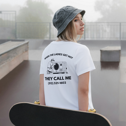 Person wearing a white t-shirt with text and a phone number, holding a skateboard in an outdoor setting. Men women unisex sized Funny tshirt, fun t shirt, when the ladies get hot, when the ladies got hot, they call me, all terrain HVAC jokes, HVAC contractor shirts